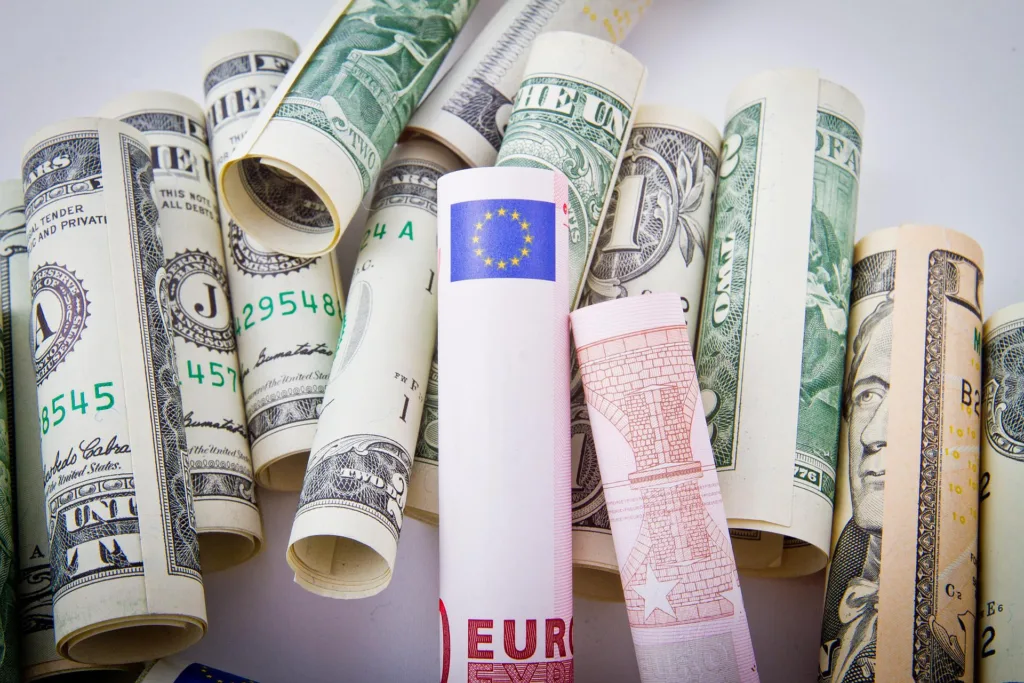 Zwinięte banknoty różnych walut, w tym euro