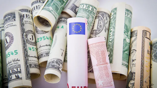 Zwinięte banknoty różnych walut, w tym euro