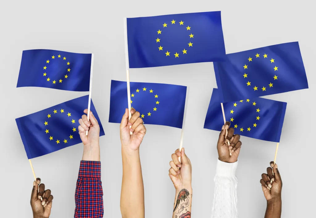 Dłonie unoszące flagi Unii Europejskiej