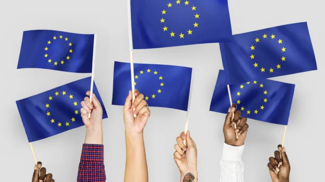 Dłonie unoszące flagi Unii Europejskiej