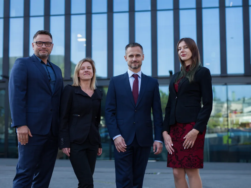 Zespół Quantus Consulting — cztery osoby przed przeszklonym biurowcem